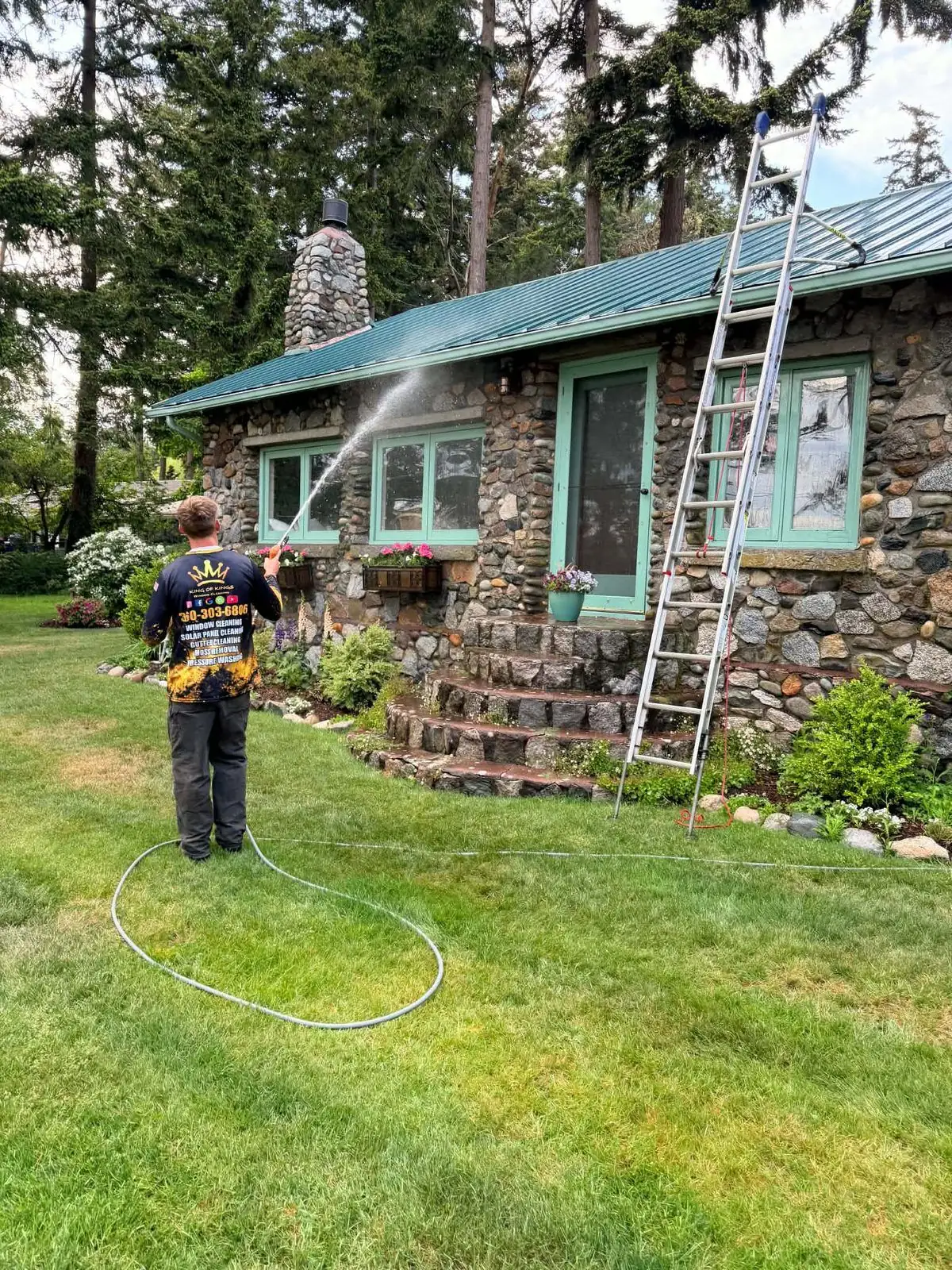 Technician protecting siding, windows and planting before soft washing a roof