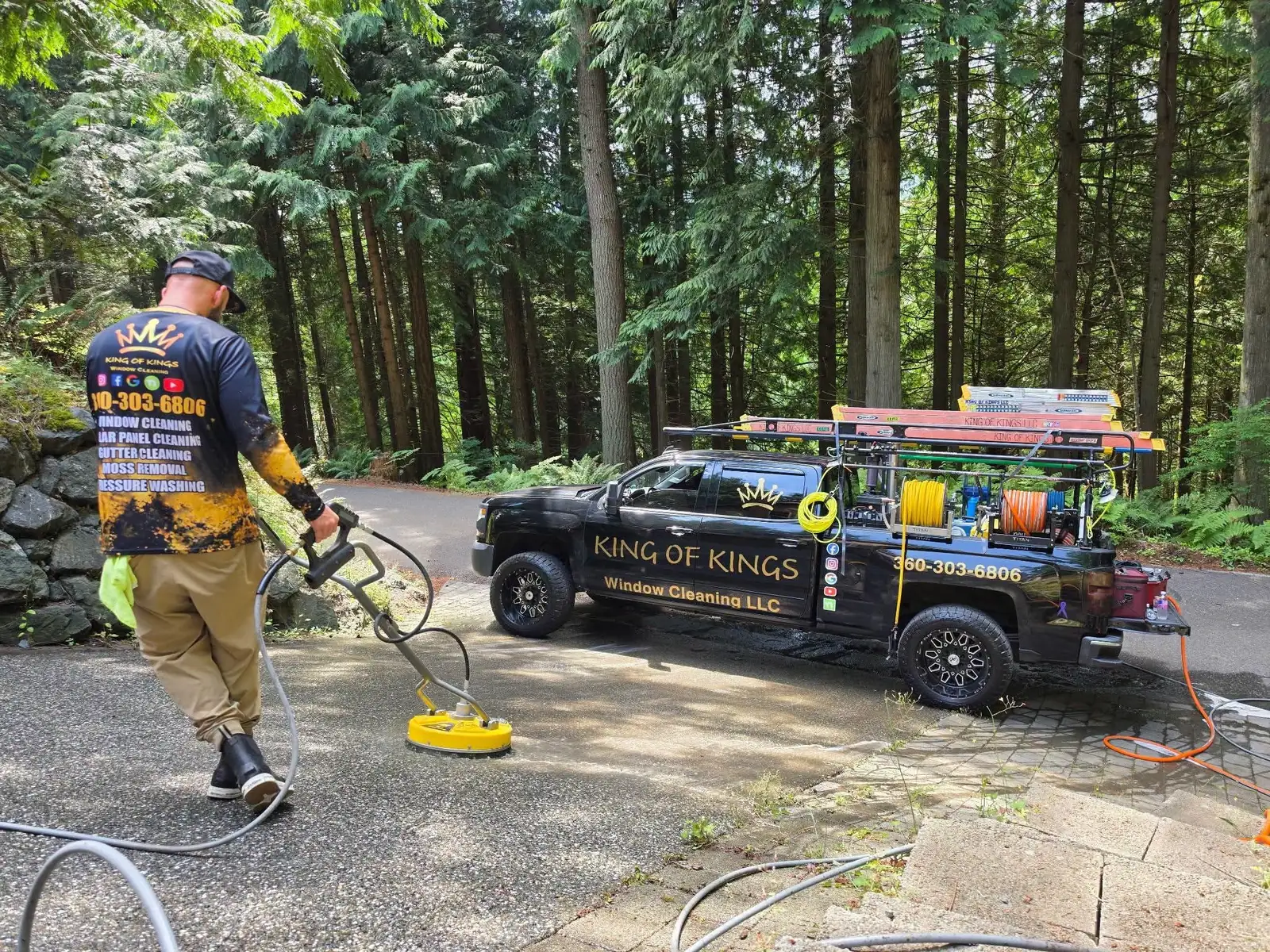 Technician running a surface cleaner across a driveway beside the branded King of Kings truck