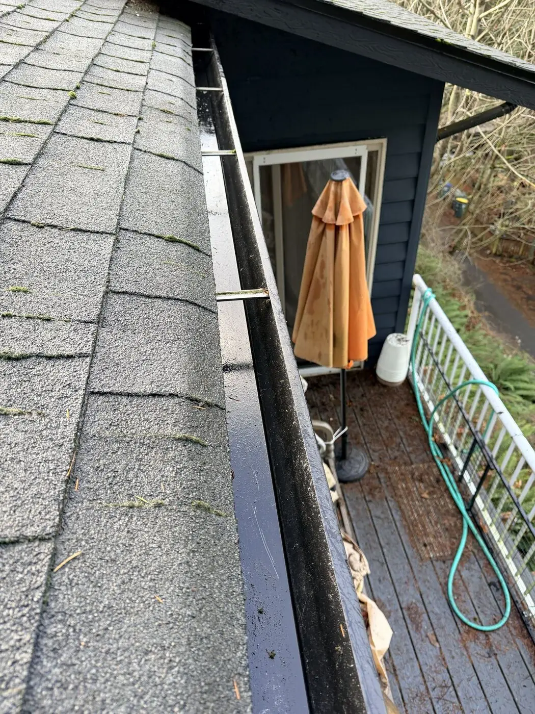 Clean, unobstructed gutter above a back deck after debris removal and flushing