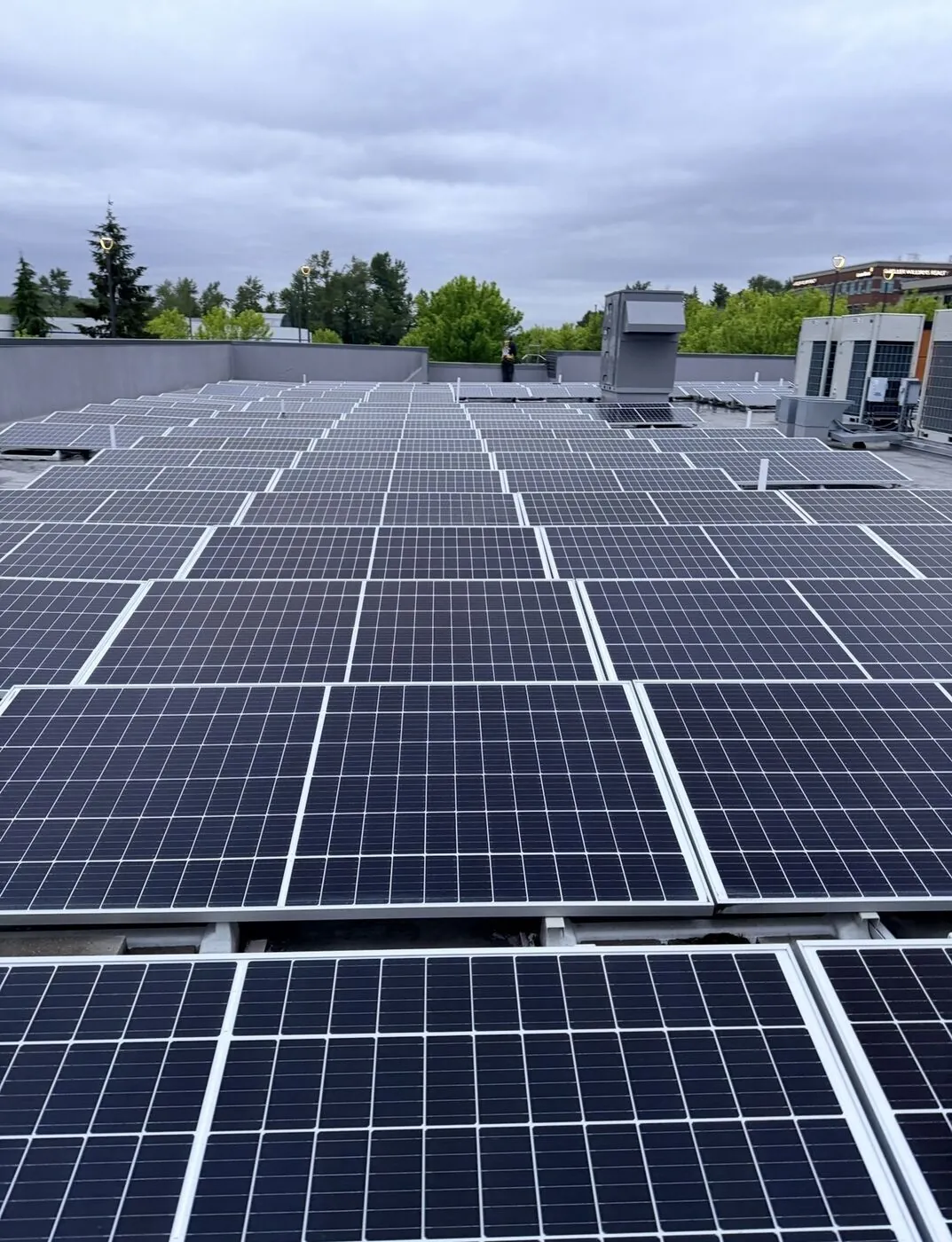 Wide view of a 128-panel commercial solar array on a flat rooftop