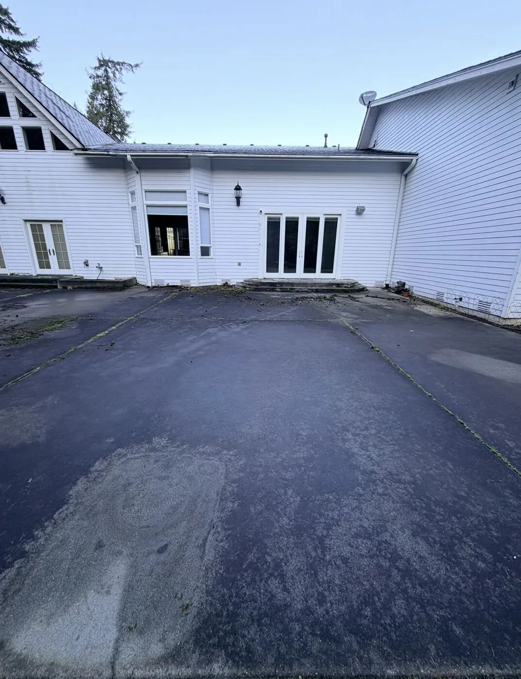 Large concrete area in front of a home, darkened almost black by organic growth