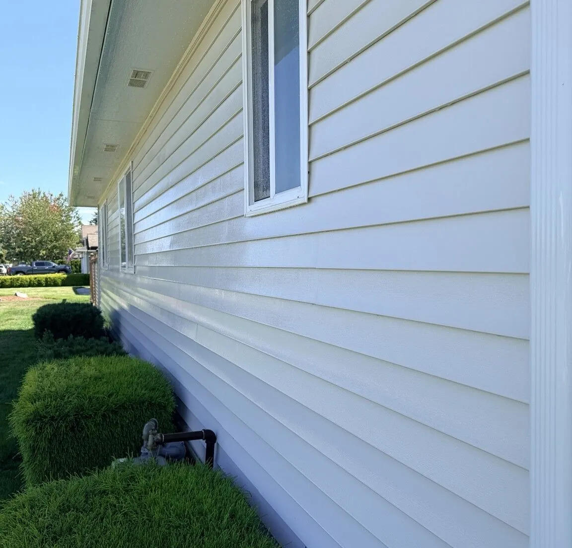 The same long exterior wall after washing, with bright, clean siding