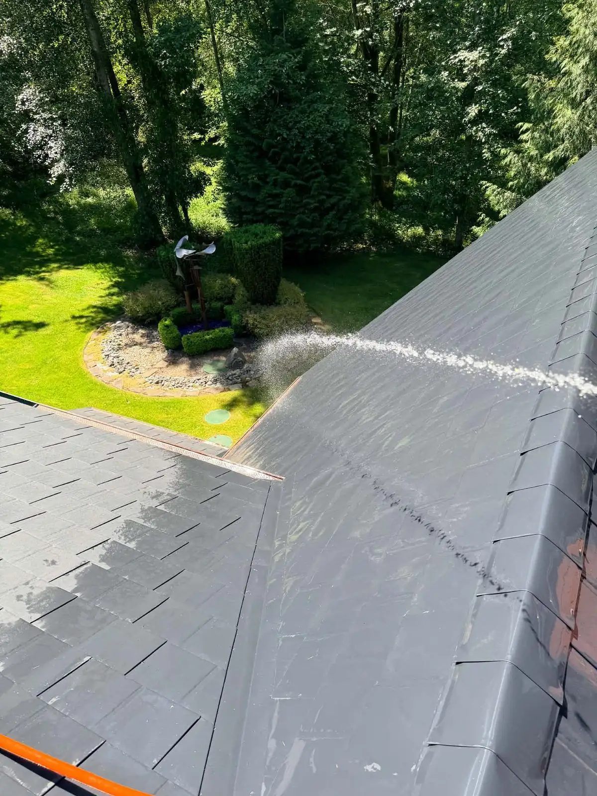 Metal shingle roof being rinsed at low pressure from a hose