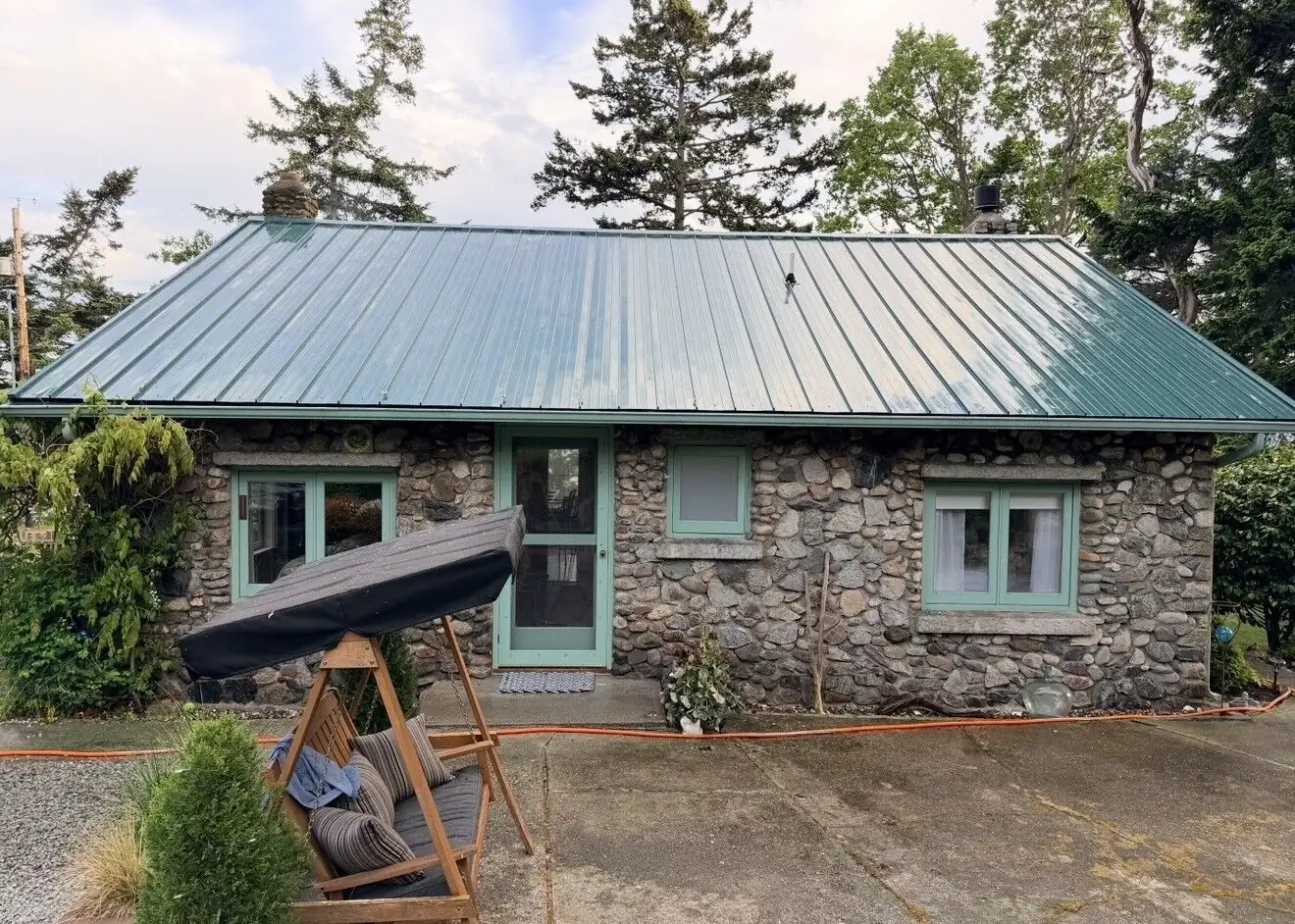 A stone home's green standing-seam metal roof in Whatcom County
