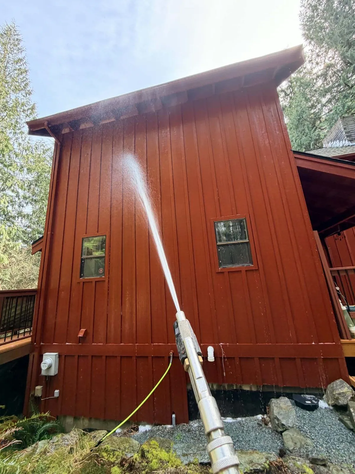 Rinsing red board-and-batten siding on a two-storey home