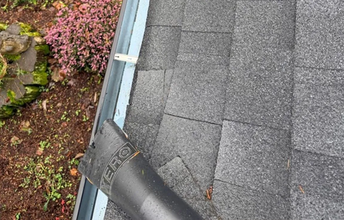 Close-up of a gray asphalt shingle roof meeting the gutter line