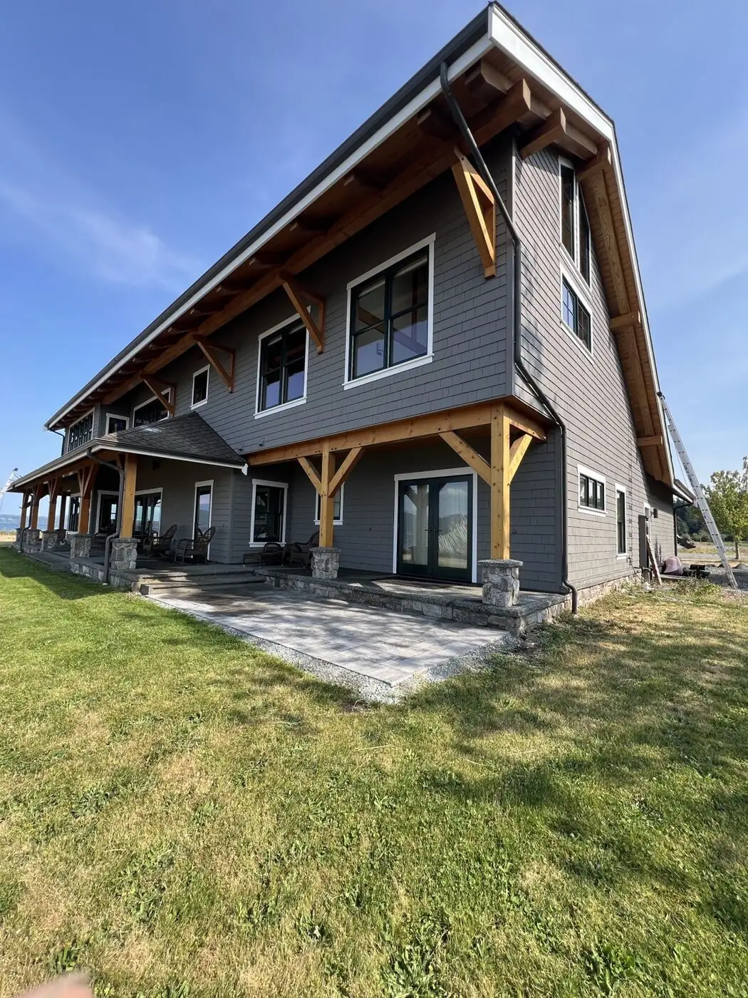 Two-storey waterfront home with large windows along a covered porch