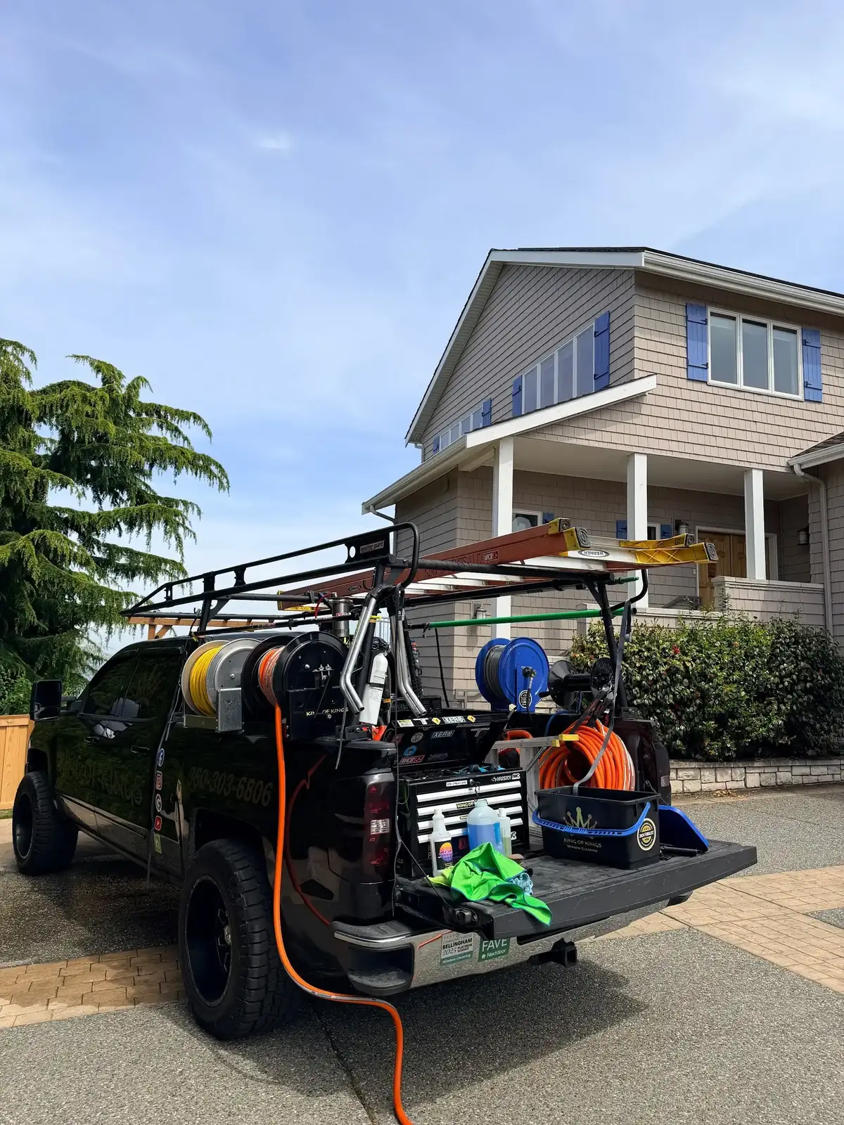 Black work truck loaded with ladders, hose reels and cleaning equipment